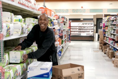 A man stocking items on a grocery shelf.