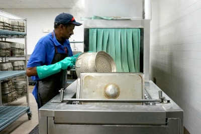 A food service worker washing dishes.