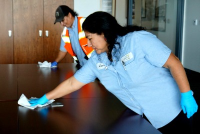 Two employees cleaning a table.